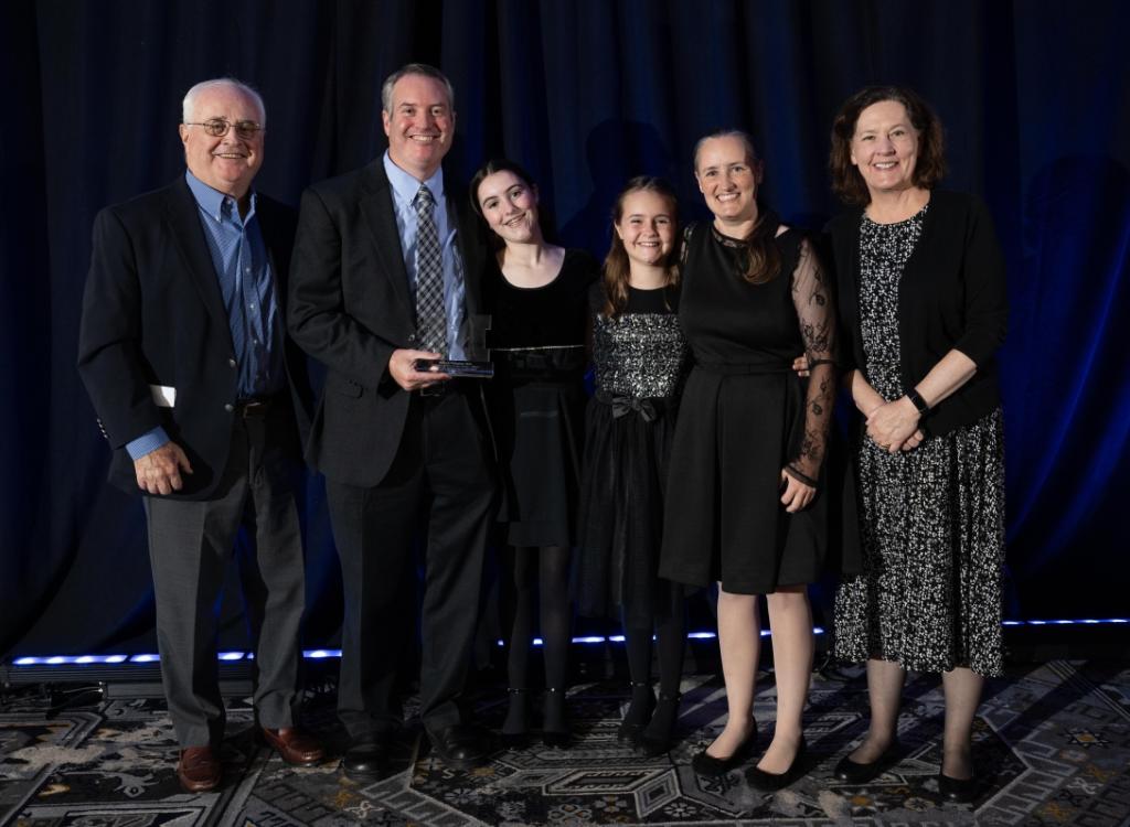 Dr. Callaghan, holding his award, standing alongside  his family.