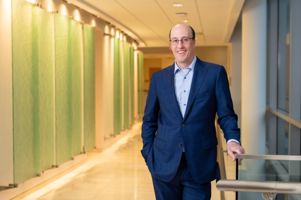 Dr. Seeley standing in a navy suit in building hallway
