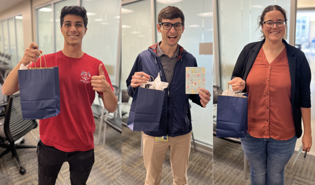 Three networking bingo winners holding blue paper bags containing their prizes