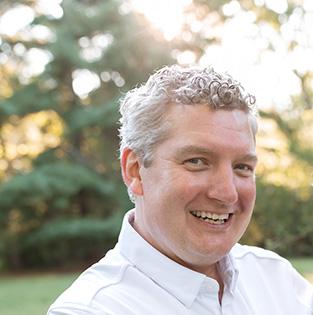 Headshot of Dr. Parker smiling outside with trees in the background