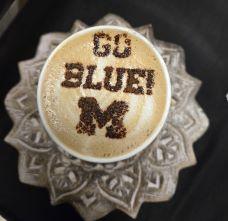 Cup of cappucino with GO BLUE and a block M on top of the foam