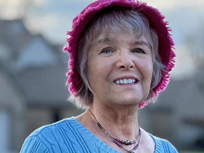 Headshot of Alice Train in pink hat with light blue sweater