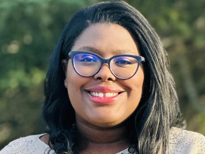 Headshot of Dr. Wolf-Fortune in tan top standing outside with what appears to be trees in the background