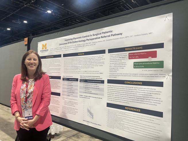 Dr. Jennifer Iyengar dressed in pink blazer standing next to her poster at the event