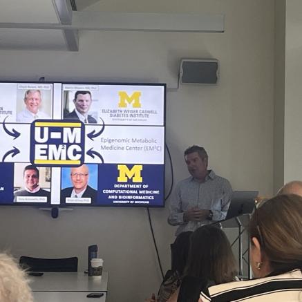 Steve Parker standing behind podium with large mounted screen to the left of him