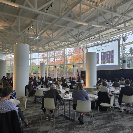 Group shot of attendees sitting around tables spread out across a large room